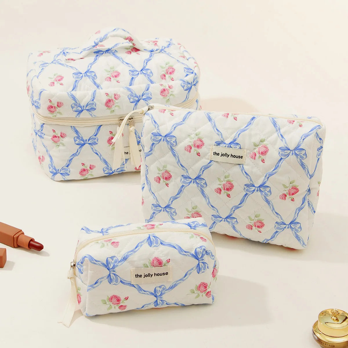 A set of quilted cotton makeup organizers in white with pink and blue floral patterns.