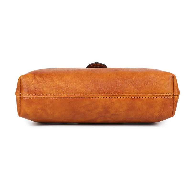 A brown genuine leather crossbody bag with a leather buckle closure.