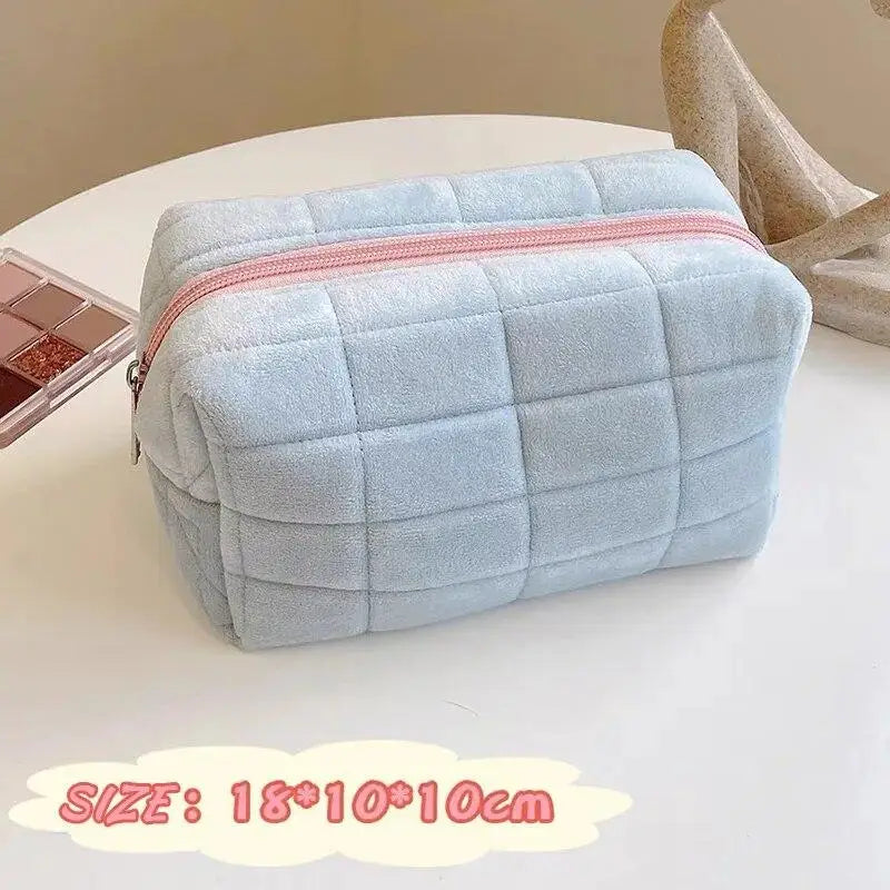 Light blue quilted zippered cosmetic storage pouch with a pink trim on a white surface.