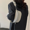 A woman holds a light beige PU leather multi-pocket crossbody bag with a silver strap against a dark blazer.