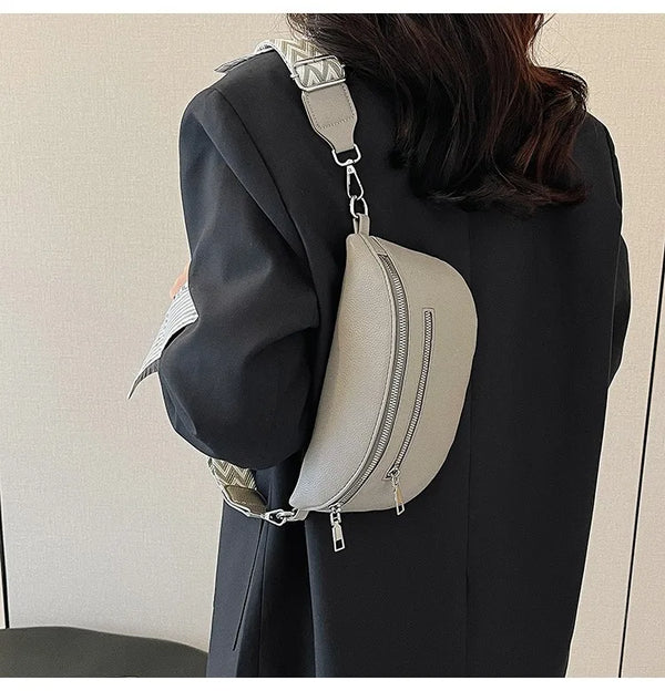 A woman holds a light beige PU leather multi-pocket crossbody bag with a silver strap against a dark blazer.