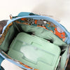 Bolsa térmica estampada en verde azulado y naranja con contenedor de plástico transparente interior.