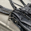A close-up of a black soft PU leather shoulder tote bag with silver hardware and leather straps.