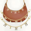 A brown leather bag with gold chain detailing and pink ribbon charms.