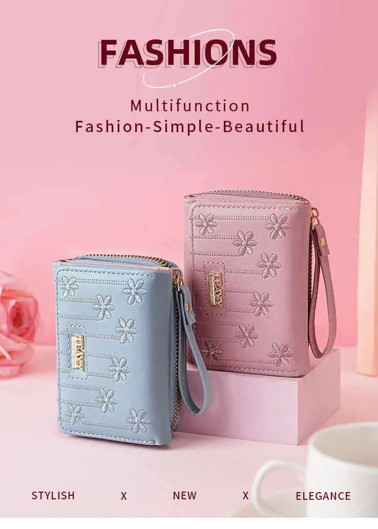A pink multifunction fashion wallet with a zipper closure and decorative floral pattern is displayed on a light pink surface.