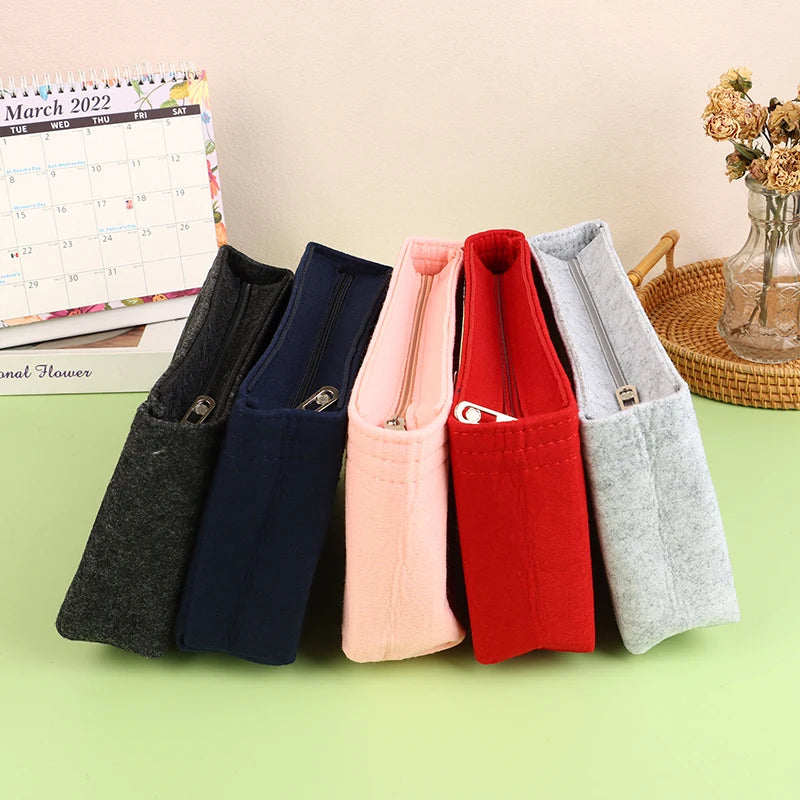 A collection of felt cosmetic bag inserts in various colors including gray, navy blue, pink, and red.
