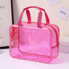 A pink glitter makeup organizer bag with a clear plastic exterior and pink handles.