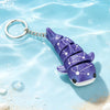 A purple 3D printed devil ray figurine with a silver chain attached, floating in clear blue water.