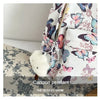 A white backpack with a butterfly pattern and a fluffy white charm hanging from the zipper.