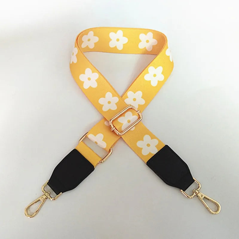 Sangle jaune avec des fleurs blanches et des accents noirs, utilisée comme sangle réglable pour sacoche.