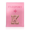 A pink leather passport holder with a gold initial K and a pink airplane design.