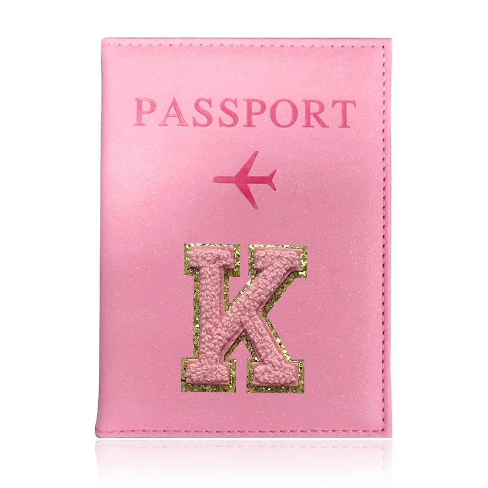 A pink leather passport holder with a gold initial K and a pink airplane design.