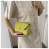 A woman holds a lime green leather crossbody bag against a beige dress.