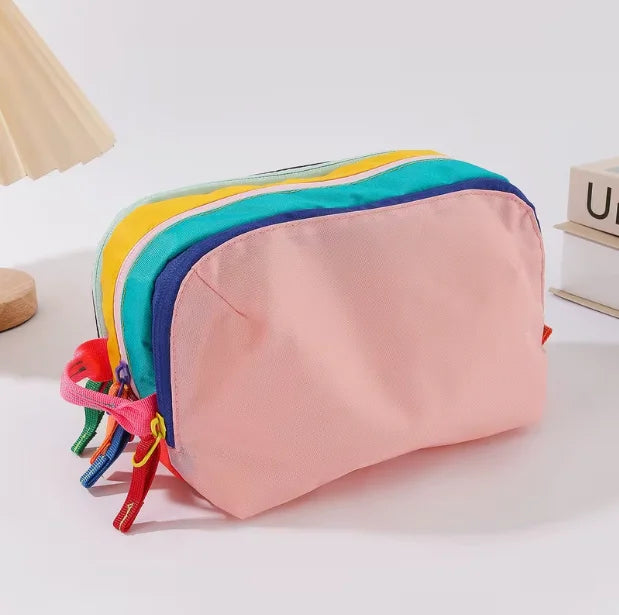 A lightweight travel makeup bag with a pastel rainbow color scheme, featuring pink and blue fabric.