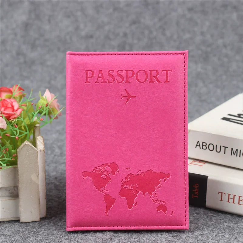 Couverture de passeport en cuir PU rose, gravée d'une carte du monde et d'un avion, posée sur une surface grise.