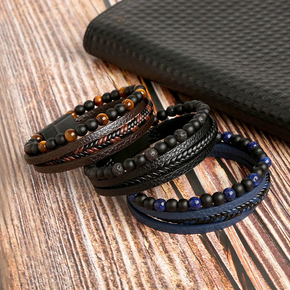A stack of multi-layer leather bracelets featuring tiger eye and dark blue beads resting on a wooden surface.