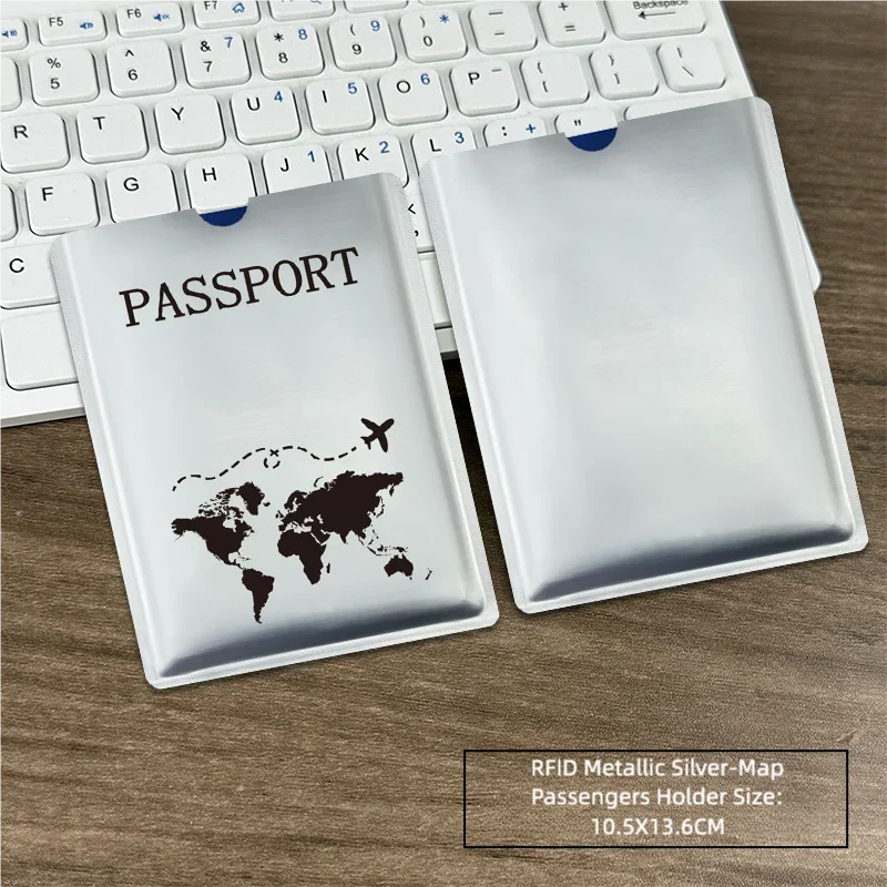 Silver RFID metallic passport holder with a world map design placed on a wooden desk next to a laptop keyboard