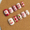 A set of cute cartoon press-on nails in red and white with various designs like Christmas and fruit on a brown surface.