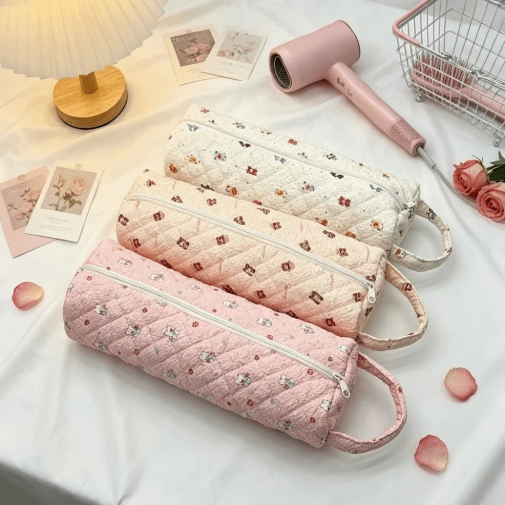 Pink quilted storage bags for hair dryers and personal items displayed on a white cloth.