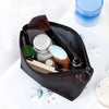 A black mesh cosmetic storage pouch containing various makeup brushes and small beauty products.