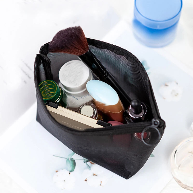 A black mesh cosmetic storage pouch containing various makeup brushes and small beauty products.