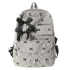 A light gray corduroy backpack with a black bow print design.