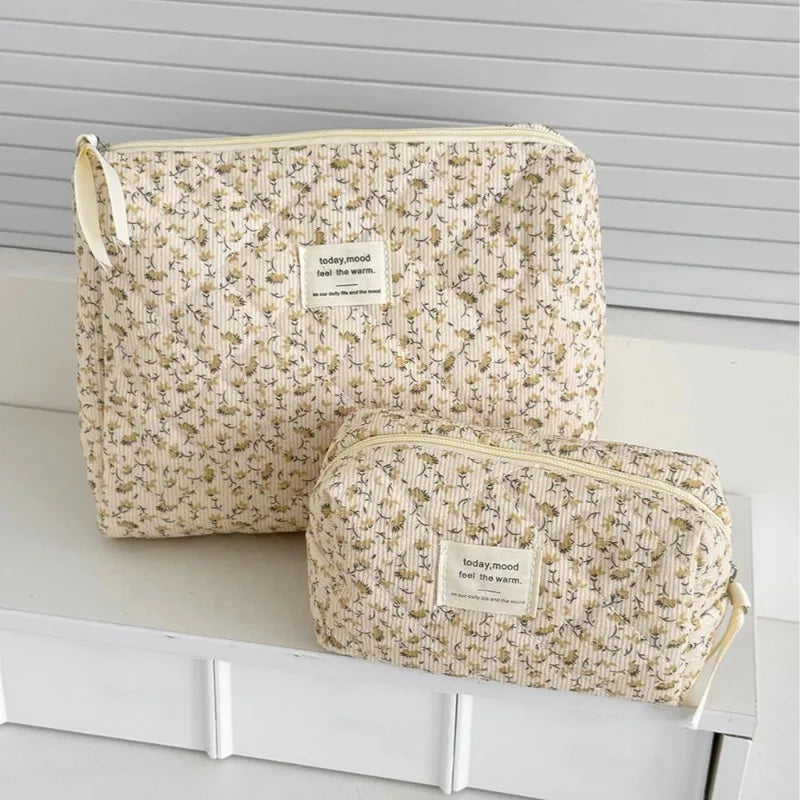 A beige floral print quilted cosmetic bag set resting on a white surface.