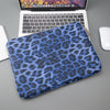Blaues Leopardenmuster-Laptop-Hülle auf grauem Untergrund neben einem Laptop.