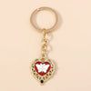 Gold heart-shaped keychain featuring a white butterfly pendant with black accents.
