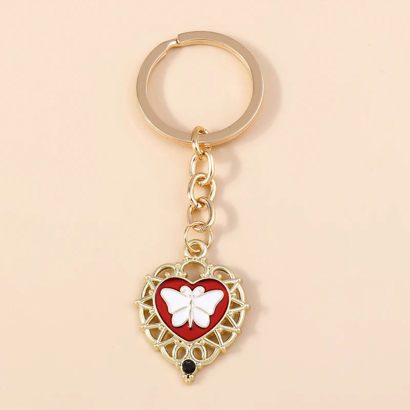 Gold heart-shaped keychain featuring a white butterfly pendant with black accents.