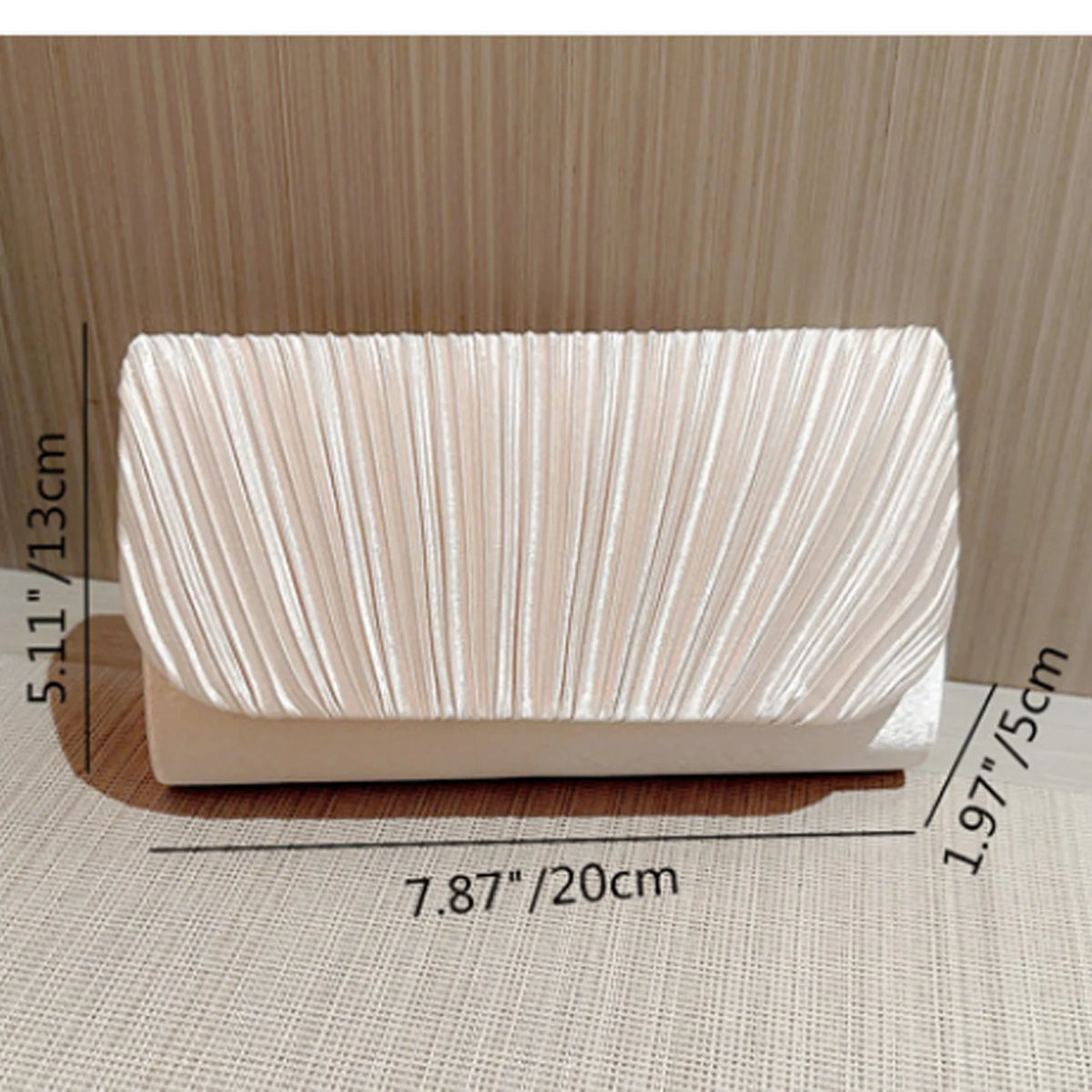A rectangular, light beige luxury chain shoulder clutch bag with vertical pleats shown on a surface.