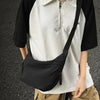 A person is wearing a black short-sleeved shirt over a white polo and carrying a black nylon crossbody bag.