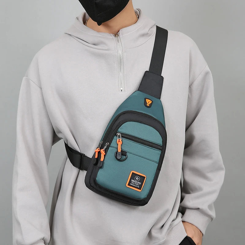 A man wearing a light gray hoodie has a dark green nylon chest bag slung across his body.