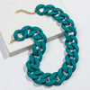 A teal matte acrylic chain necklace with a gold clasp is displayed on a white surface.