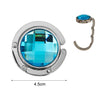 A round acrylic foldable hook with a blue lens and silver metal ring for bags and keys.