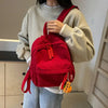 A person is wearing a red lightweight corduroy daily backpack over a cream sweater.