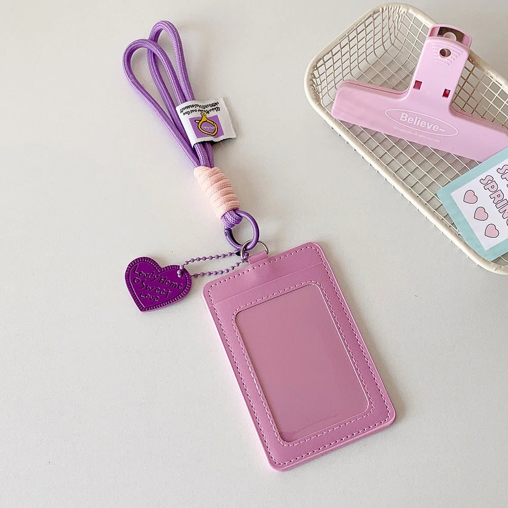 A pink PU credit card and ID holder keychain with a purple lanyard and a pink plastic holder on a white background.