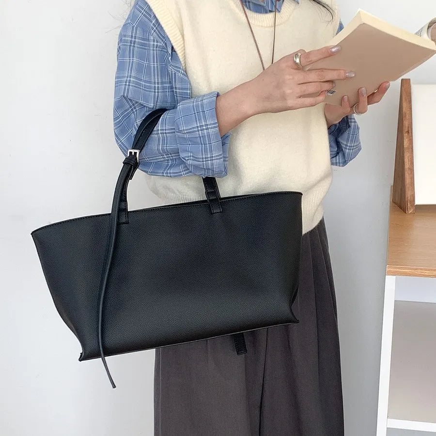Une femme tient un sac à main noir en cuir PU décontracté sur fond blanc.