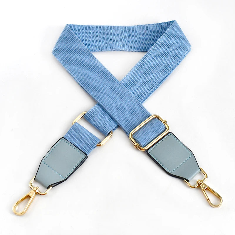 A light blue canvas cotton bag strap with gold-colored metal hooks, shown in an 'X' shape.