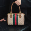 A brown and beige patterned leather tote bag with green and red stripes is held by a person.