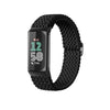 A black stretchy nylon watch band for a Fitbit device is shown coiled on a white background.