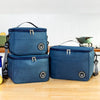 A navy blue insulated portable lunch bag with a shoulder strap is shown on a wooden surface.