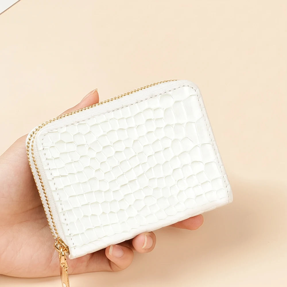 A hand holds a white crocodile print PU leather double zipper wallet against a light beige background.