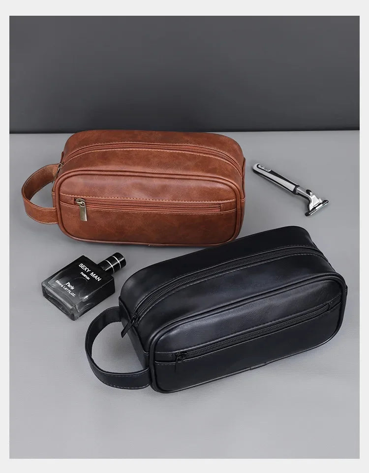 A brown leather travel cosmetic bag next to a black leather bag and a silver metal object.