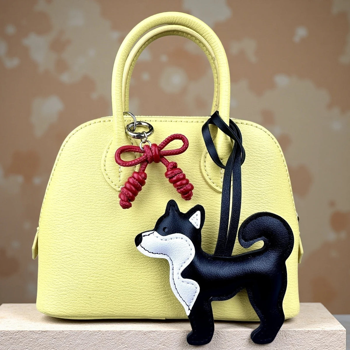 Bolso de cuero amarillo con un dije de perro Shiba Inu negro y un lazo de cuero rojo trenzado a mano.