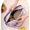 A hand is opening a purple insulated lunch bag to show its interior, with a lemon nearby.