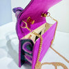 A vibrant magenta clutch bag featuring purple sequins and gold chain detailing.