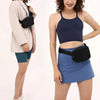 A woman models a navy blue crop top and light blue skirt with a black waist bag.