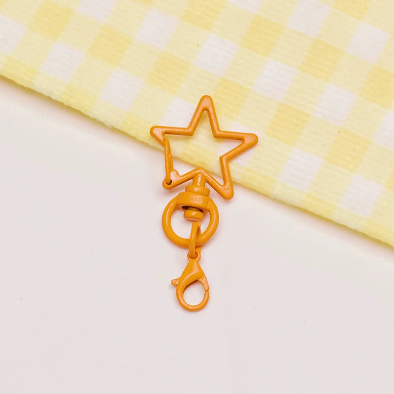 A small, gold-toned metal keychain clasp set shaped like a star and a ring, resting on a yellow checkered cloth.