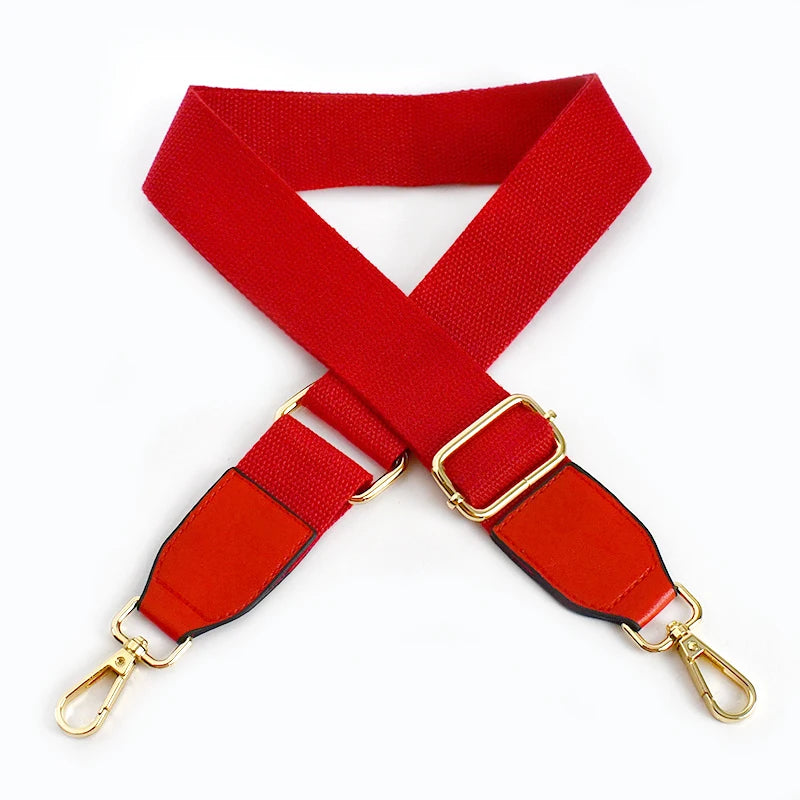 A red canvas cotton bag strap with gold-colored metal hooks, shown in an 'X' shape.